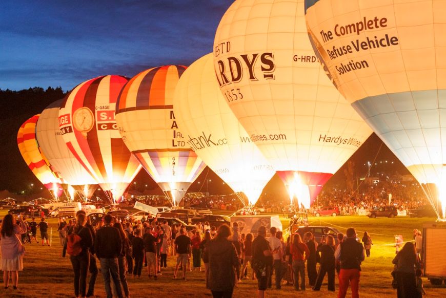 Hot air balloons on the ground, lighting up at night